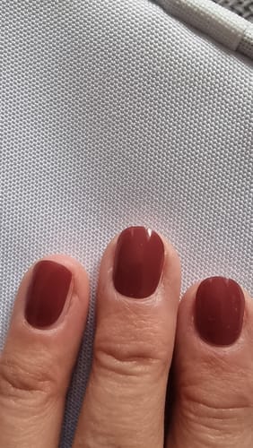 Nahaufnahme der manikürten Nägel einer Kundin, die die tiefroten UV-Gel-Nagelfolien „Sweet Sienna“ trägt.