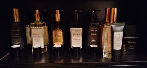 Recensent toont de Istanbul Handcrème in een zwarte tube als onderdeel van een grote productcollectie op een plank.