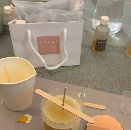 Customer's view of the Candle Making Workshop setup, including a newly poured candle, tools, and a branded Yougi gift bag.