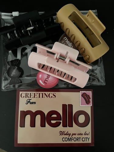 Customer's three cloud clips in black, beige, and pink displayed with their packaging and a brand postcard.