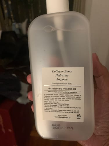 Reviewer's hand holding the large bottle of Bad Skin™ Korean Collagen Bomb Hydrating Ampoule, showing the product label.