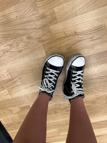 Reviewer wearing the black-and-white Roam I barefoot shoes while standing indoors on a wooden floor.