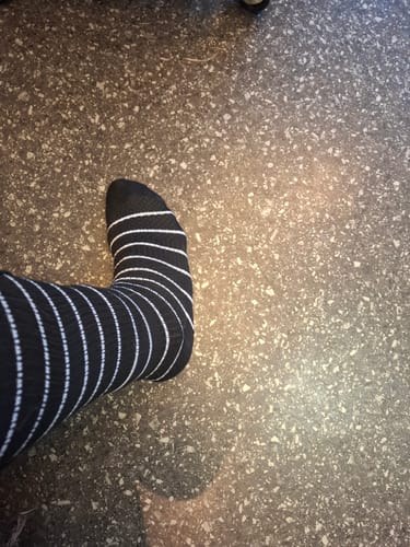 Recensent som bär en svart och vitrandig Diasocks stödstrumpa på foten.