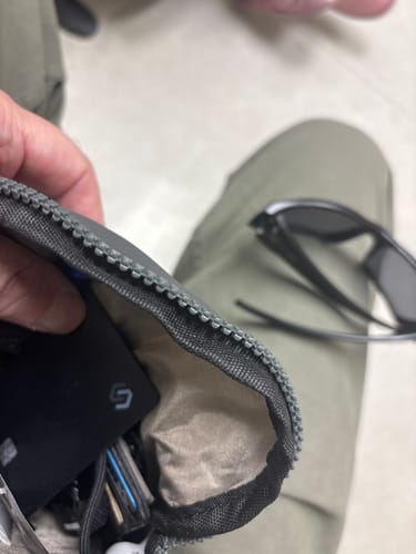 Reviewer holding open a small pouch, showing the black SPOTMINDERS Tracking Card PRO inside.