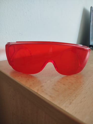 Reviewer's red VisionX blue-light blocking glasses resting on a wooden surface.