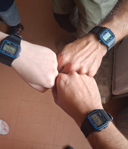 Clientes mostrando sus tres relojes idénticos Casio F-91W-1DG con los puños juntos.