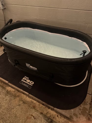 Reviewer's black, oval Long Pod filled with water and set up for an ice bath on a mat.