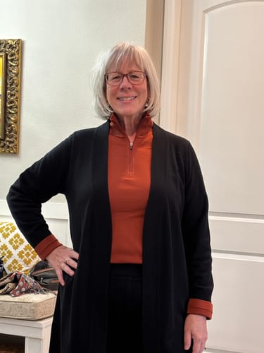 Customer wearing the Brooke 1/4 Zip in Maple Leaf as a comfortable base layer under a black cardigan.