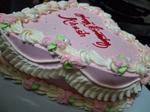 A reviewer's pink Sagittarius Zodiac Theme Cake showing its detailed vintage piping and red birthday message.