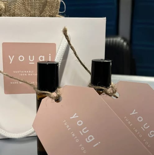 Customer's two finished perfumes from the workshop, in amber rollerball bottles with branded Yougi tags.