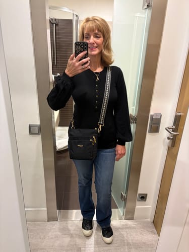 Reviewer wearing the black Charlotte Puff Sleeve Top with blue jeans, showing the Henley-style button front.