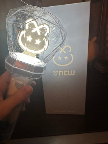 Customer holding the ONEW OFFICIAL LIGHT STICK, lit with a white light, with its box in the background.