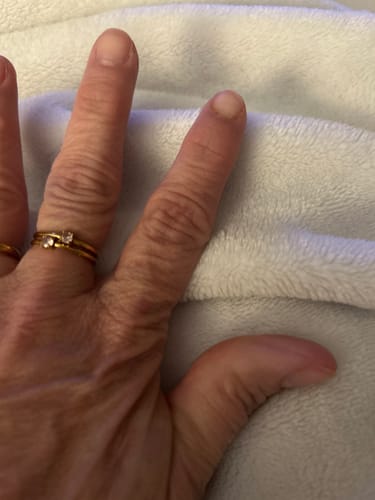 Reviewer's hand wearing the December Birthstone 18K Gold Ring stacked with another gold band.