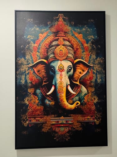 Reviewer's vibrant Tranquil Ganesha canvas print mounted in a black frame on a wall.