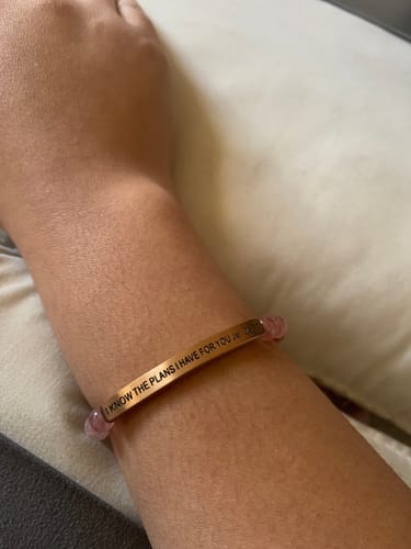 Close-up of a reviewer's arm wearing the rose gold bracelet with pink beads, engraved 'I KNOW THE PLANS I HAVE FOR YOU'.