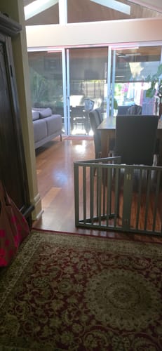 Reviewer's grey Wooden Pet Gate partially folded and standing to the side of a doorway.