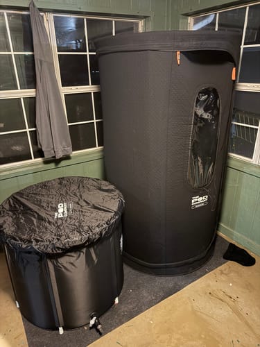 Customer's black Sauna Pod 2.0 set up in a room next to a matching cold plunge tub.