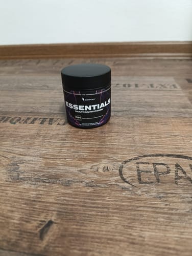 Customer's black tub of Essentials Multivitamin resting on a wooden floor.
