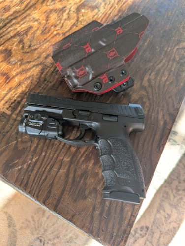Customer's black and red patterned XIPHOS V2 holster next to a handgun on a wooden table.