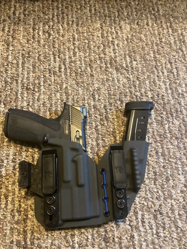 Customer's black AXIS ELITE holster with blue cord, shown with a firearm and magazine fitted inside.