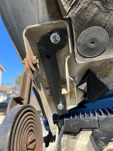 Customer's close-up view of the black hood ditch light mount installed on the truck's hood hinge.