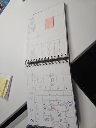 Customer's open Nancy Planner on a desk, showing the monthly and weekly layouts filled with handwritten notes.
