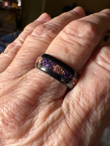 Reviewer's hand wearing the Amareus ring, showing the black band with amethyst and gold leaf inlay.