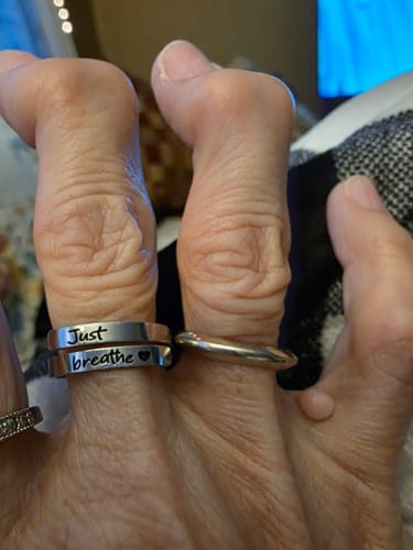 Close-up of a reviewer's hand wearing the silver-tone Just Breathe Ring, showing the "Just breathe" engraving.