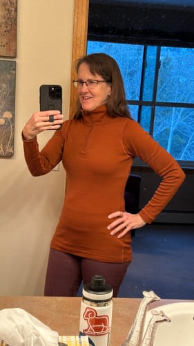 Reviewer taking a mirror selfie in the sleek, rusty orange Brooke 1/4 Zip top, showing its fit.
