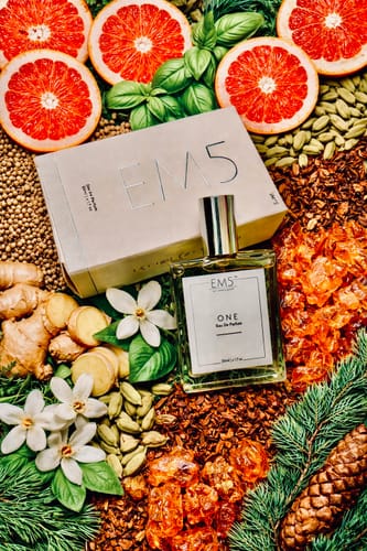 Reviewer's One | Eau De Parfum bottle and box in a flat lay showing its fresh citrus and spicy ingredients.