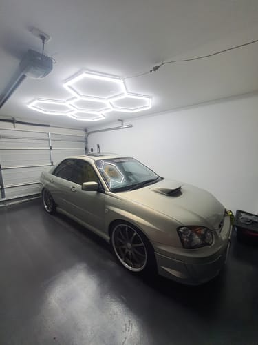 Customer's bright Hexagon LED Lights installed on a garage ceiling, illuminating a car parked below.