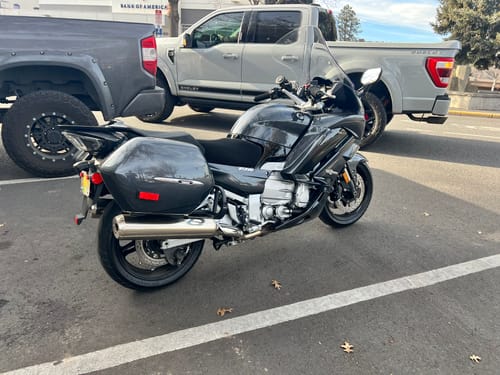 Customer's grey motorcycle parked outside, with the black mesh Wind Rider Seat Cover on the seat.