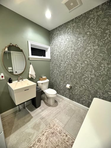 Reviewer's laundry room featuring the green Winsome Wallpaper as an accent wall next to a toilet and sink.