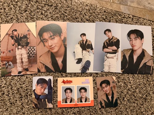 Reviewer displays various photo cards from their K-POP RANDOM BOX, featuring an ATEEZ member, laid out on a carpet.