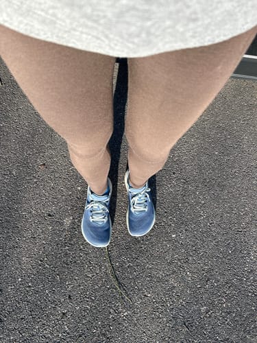 Customer's legs in the brown Piper Pocket Tall leggings, viewed from above while standing outdoors on pavement.