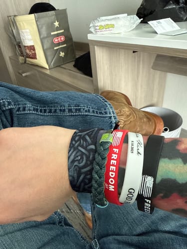 A close-up of a reviewer's wrist wearing the Guardians Wolf Bracelet in a stack with several other bracelets.