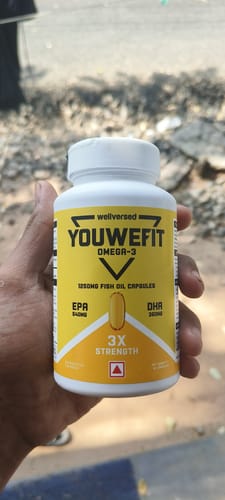 Reviewer holds a bottle of YouWeFit Omega-3 Fish Oil, showing the yellow '3X Strength' label.