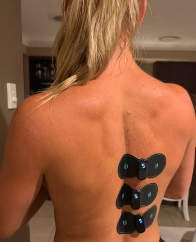 Reviewer with three Vibit TENS devices attached vertically to their back, showing the product in use.