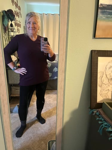 Reviewer taking a mirror selfie wearing a purple long-sleeve top and black bottoms.