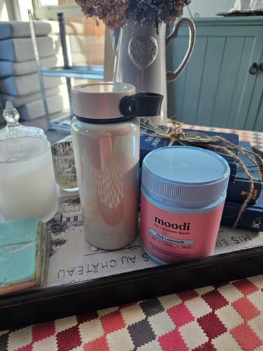 Customer's Moodi Pink Lemonade tub sitting on a decorative tray next to a takeaway bottle.