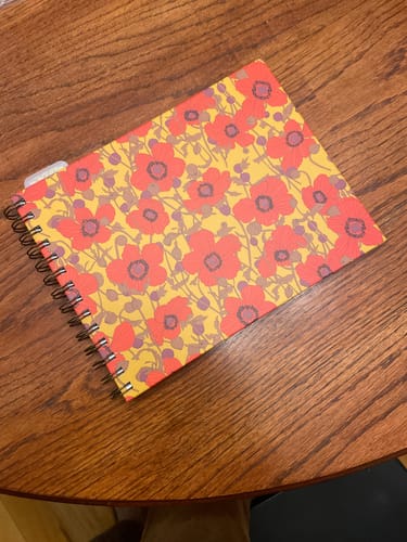 Customer's Rose Planner with a vibrant floral cover, closed and lying on a wooden table.