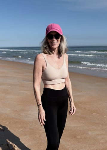 Reviewer wearing the sand-colored Hayden Bra and black leggings on a sunny beach.