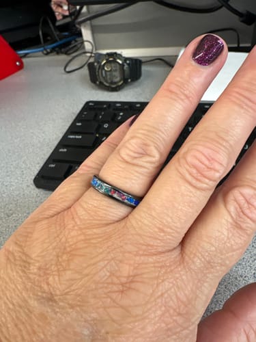 Reviewer's hand wearing the black Titanium Carbide Ring with a colorful cremation ash and opal inlay.