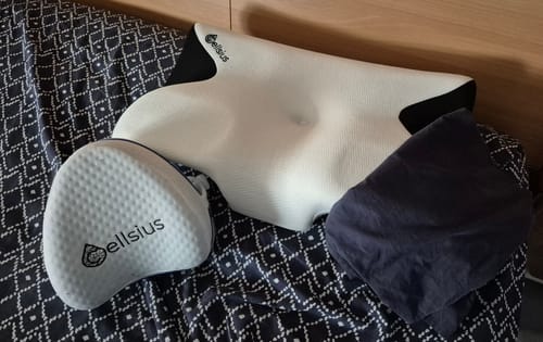 Un client montre ses deux coussins Cellsius, un blanc et un gris, sur une couverture à motifs.
