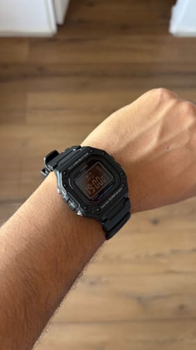 Cliente mostrando su reloj Casio Vintage negro en la muñeca, que marca las 19:00.