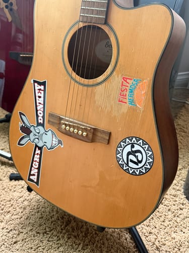 Customer's three custom stickers from the sale displayed on a light brown acoustic guitar.