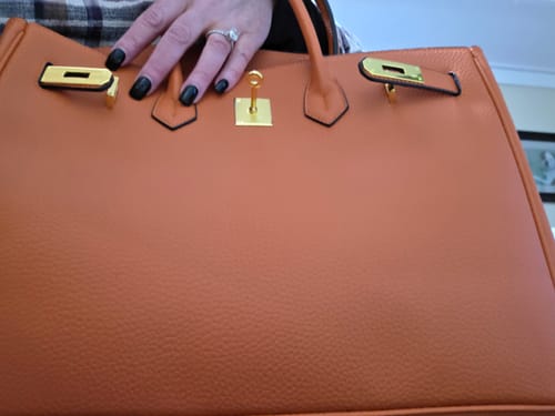 Close-up of a reviewer's deep orange Warkin Bag, showing the pebbled leather and gold hardware.