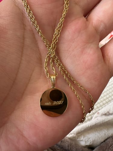 Customer holding the gold Engravable Classic Disc Necklace. The round pendant is engraved with 'est. 2021'.