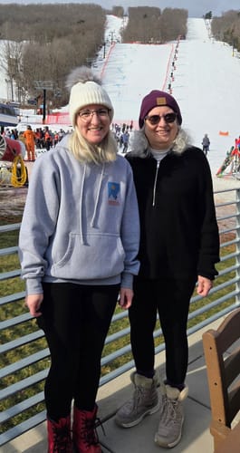 Two customers wearing black Piper Pocket Leggings while standing outdoors at a snowy ski resort.