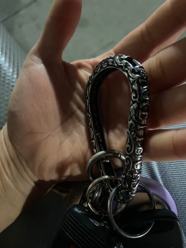 Customer holding the ornate Catacombs Carabiner in their hand with a set of keys attached.